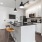 Two Bedroom Apartments in Union Hill, Kansas City, MO - Gallerie Apartments - Modern Kitchen with Stainless Steel Appliances, Black Granite Countertops, White Cabinetry, Tile Backsplash, and a Large Cooking Island with Stools and a Sink